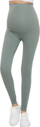 Wholesale maternity leggings in sage green with high waistband and ankle cuffs, paired with white sneakers